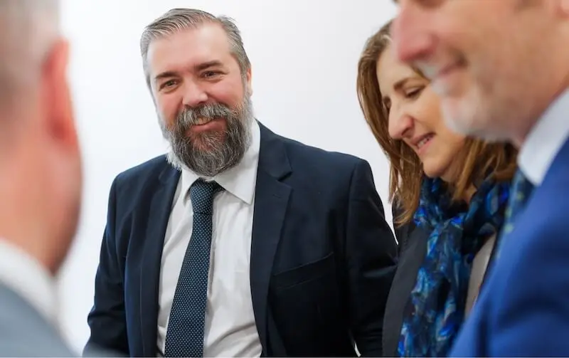 Abogados de Javaloyes Legal conversan sonrientes durante una reunión de equipo en el despacho.
