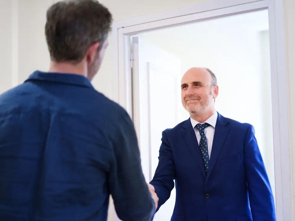 Miguel Javaloyes recibe con un apretón de manos a un cliente en la entrada del despacho Javaloyes Legal.