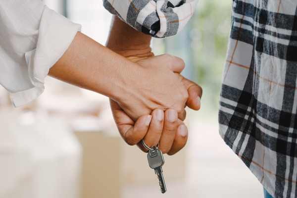 Pareja dándose la mano con una llave, simbolizando el asesoramiento en la compra de una vivienda.
