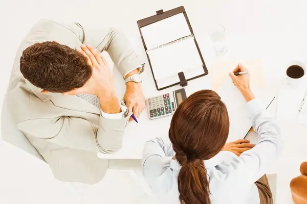 Hombre preocupado frente a una asesora, ilustrando el proceso legal y humano de despedir a un trabajador.