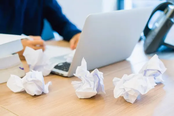 Mesa con papeles arrugados y ordenador, reflejando frustración ante un despido por ineptitud sobrevenida.