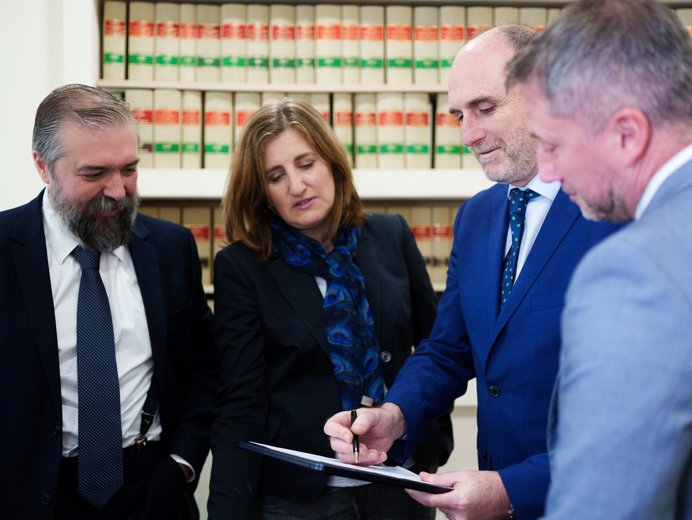 Equipo legal de Javaloyes Legal revisa y firma documentos jurídicos durante una reunión en su despacho.