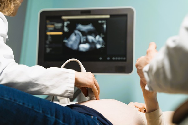 Profesional realiza ecografía a mujer embarazada, ilustrando una posible negligencia médica durante el parto.