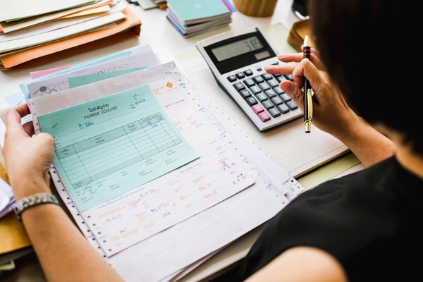 Persona revisando nóminas y usando calculadora para reclamar salarios impagados.