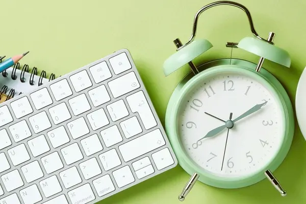 Reloj y teclado sobre escritorio, representando la reducción de la jornada laboral y la gestión del tiempo.