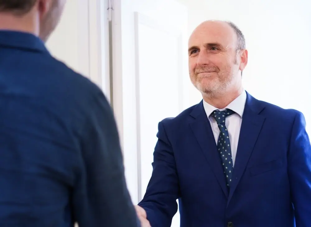 Miguel Javaloyes, abogado, recibe con un apretón de manos a un cliente en la entrada del despacho.