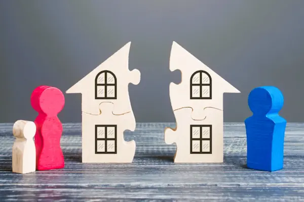 Figuras de familia separadas por una casa partida, simbolizando la extinción de condominio tras el divorcio.