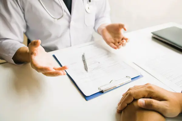 Médico dialogando con paciente frente a documentos, ilustrando la falta de consentimiento informado en negligencias médicas.