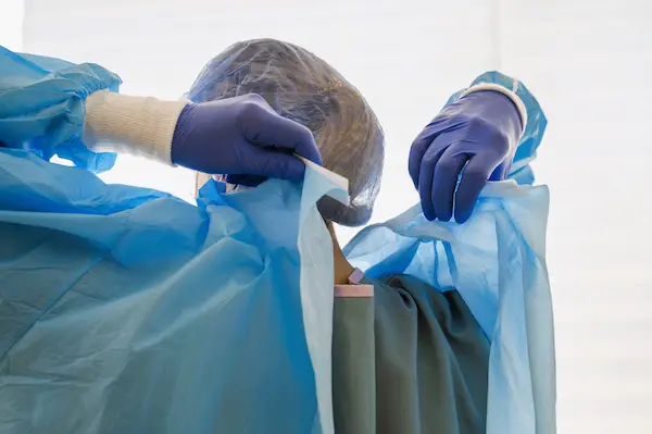 Profesional sanitario con bata y guantes prepara procedimiento, ilustrando negligencia médica por epidural mal puesta.