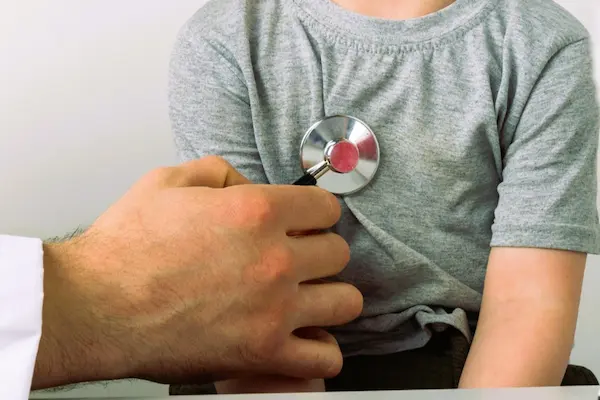 Médico ausculta el pecho de un niño, ilustrando un caso de posible negligencia médica pediátrica.