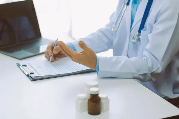 Médico con bata blanca escribe en un formulario clínico, ilustrando el contexto de negligencias médicas.
