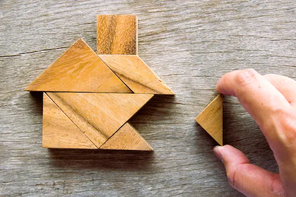 Piezas de madera en forma de casa representan un proindiviso, propiedad compartida sin división material.