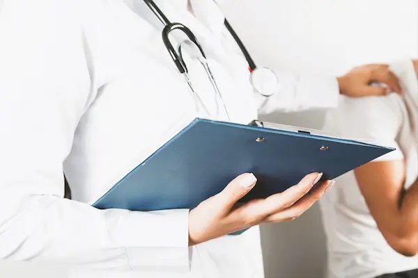 Médico con historial clínico junto a paciente, ilustrando la duda legal sobre demandar por diagnóstico erróneo.
