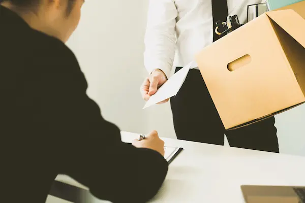 Empleado entrega una carta de despido con una caja de pertenencias, simbolizando un cese con contrato indefinido.