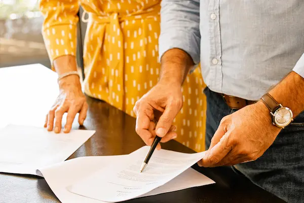 Dos personas revisan y firman documentos legales, representando el reparto de la herencia legítima.