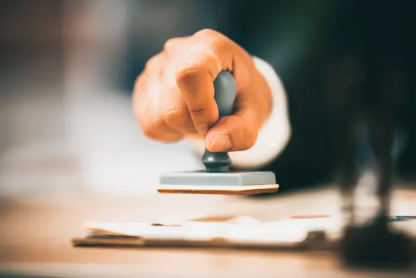 Mano estampando un sello sobre documentos, representando la tramitación legal de una herencia sin testamento.