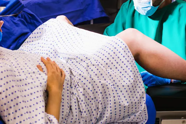 Mujer en sala de parto atendida por personal médico, representando una hemorragia postparto por negligencia.