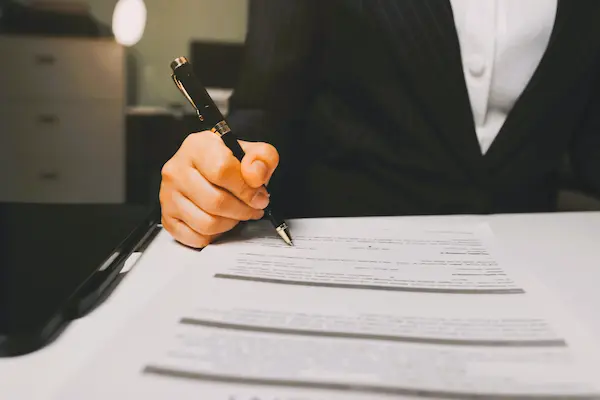 Mano con bolígrafo lista para firmar documento legal, representando la papeleta de conciliación laboral.