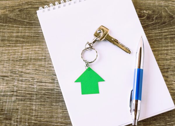 Llaves con llavero en forma de casa sobre libreta y bolígrafo, simbolizando conflicto en la venta de herencia.