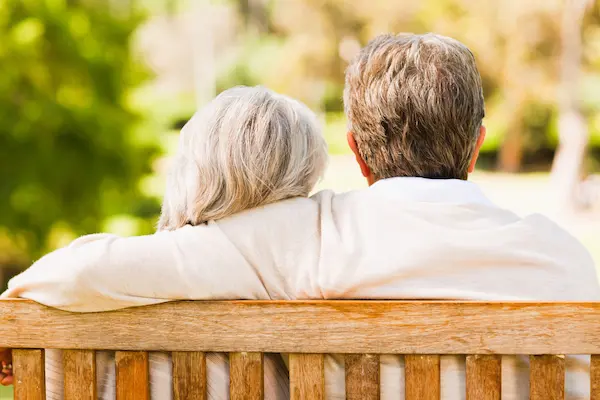 Pareja de personas mayores sentada en un banco, representando el contexto de una herencia sin descendencia directa.