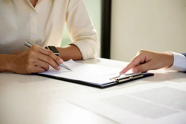 Dos personas revisando un documento legal, ilustrando dudas sobre si un hijo puede reclamar la herencia del padre fallecido a su madre.