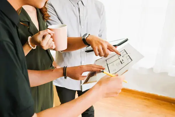 Personas revisan plano arquitectónico, en relación con el proceso legal de segregación de vivienda en Madrid.