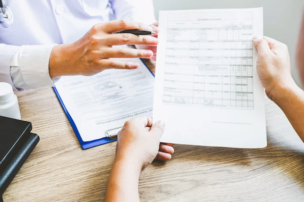 Dos personas revisan una tabla de datos médicos en consulta, representando la indemnización por negligencia médica.