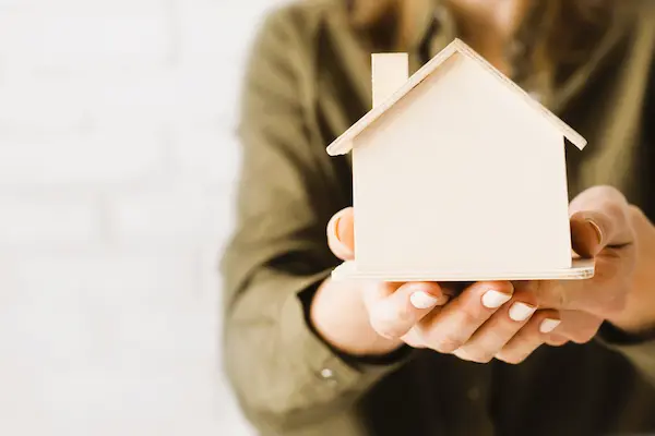 Manos sostienen maqueta de casa, representando el derecho de usufructo vitalicio sobre un bien inmueble.