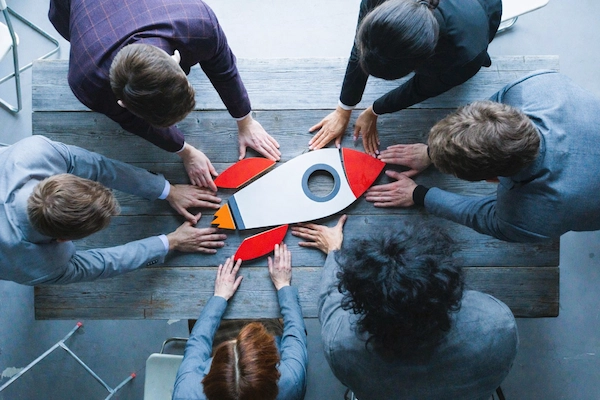 Equipo rodea una figura de cohete sobre una mesa, simbolizando el lanzamiento de una startup en Madrid.