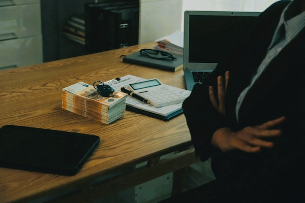 Mesa con fajos de billetes, llaves y documentos, vinculada al delito de administración desleal en el ámbito empresarial.