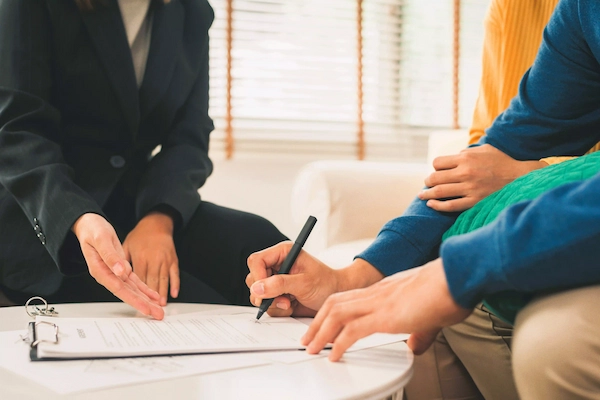 Persona firmando documentos junto a asesor legal, ilustrando el concepto de herencia yacente en derecho sucesorio.