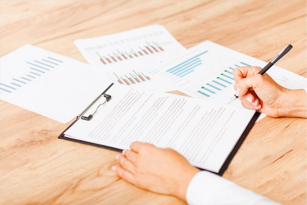 Persona redactando acuerdo junto a gráficos financieros, representando acuerdos phantom shares en España.