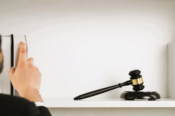 Un profesional jurídico consulta un libro junto a un mazo judicial, representando el recurso extraordinario de revisión, un mecanismo legal que permite impugnar sentencias firmes cuando aparecen hechos nuevos o pruebas relevantes.