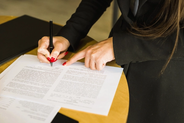 Abogada firma documento legal en una mesa, ilustrando los plazos para dictar sentencia en un juicio de lo social.