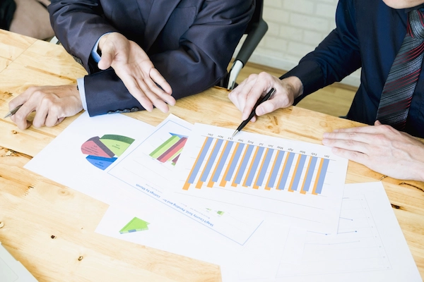 Dos empresarios analizan gráficos financieros, ilustrando el proceso de valoración de una empresa para su venta.