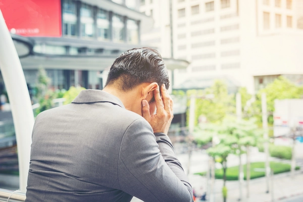 Hombre de negocios preocupado con gesto de estrés; representa las consecuencias del delito societario.