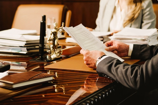 Manos de abogado revisando documentos legales en una mesa, representando la distribución de herencias forzosas.