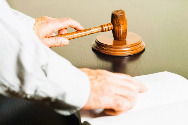 Mano de juez con mazo sobre la mesa consulta libro jurídico, simbolizando el interés casacional objetivo.