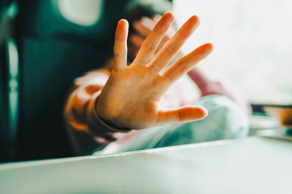 Persona con la mano extendida en señal de rechazo, representando una situación de posible acoso laboral.