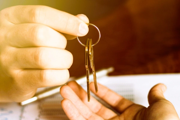 Una mano entrega llaves a otra sobre documentos, simbolizando el conflicto de uso entre usufructuario y nudo propietario.