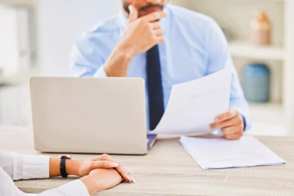 Abogado revisando documentos ante un trabajador para explicar cómo actuar ante una denuncia laboral.