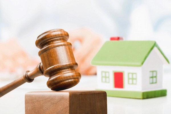 Mazo de juez junto a maqueta de vivienda que representa el derecho de retracto del inquilino en la compra del inmueble alquilado.