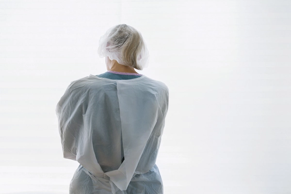 Sanitaria de espaldas con bata, representando casos de mala praxis médica y responsabilidad profesional.