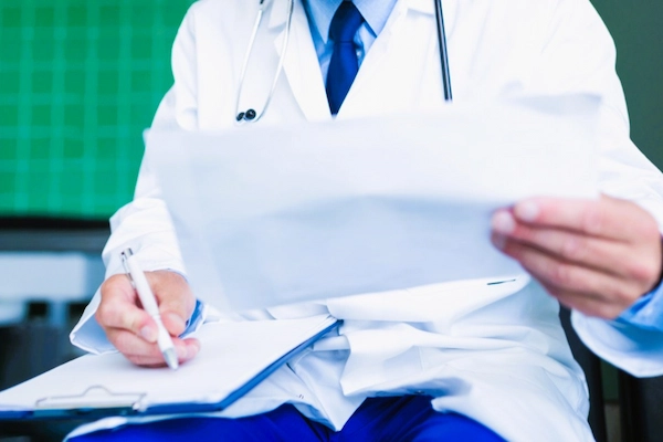 Médico revisando informe clínico, relacionado con imprudencia profesional y negligencias médicas.