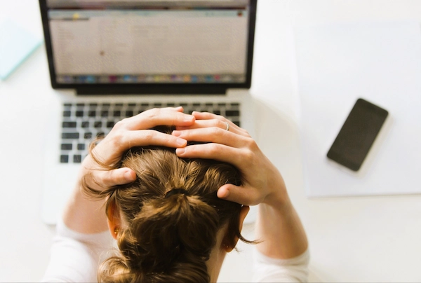Persona con gesto de estrés frente al ordenador, reflejo del impacto laboral y emocional de una denuncia por acoso en el trabajo