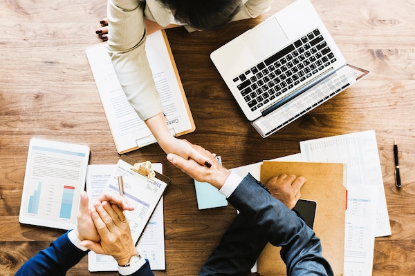 Apretón de manos en mesa de trabajo simboliza crear una sociedad limitada, empresa con responsabilidad limitada de socios