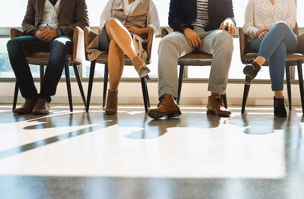 Personas sentadas en una sala de espera laboral que representa un despido colectivo, extinción simultánea de contratos por causas económicas o empresariales.