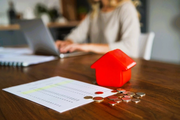 Documentos de hipoteca con monedas y una casa roja, representación del IRPH, índice usado en España para calcular intereses hipotecarios.