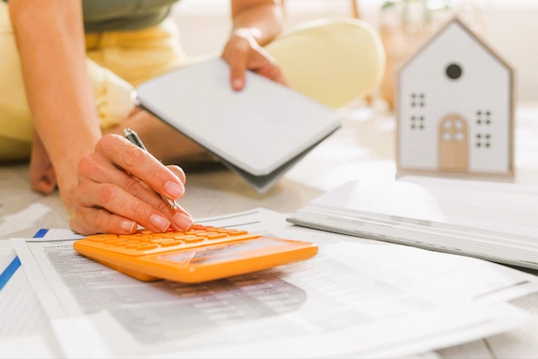 Persona calculando gastos de hipoteca con calculadora y documentos, ilustrando la reclamación de costes hipotecarios al banco.