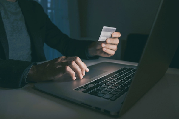 Persona realizando una operación con tarjeta en un portátil, relacionado con fraude bancario y reclamación para recuperar el dinero